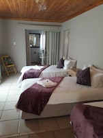 Quarto de hotel com duas camas, teto de madeira e vista para uma varanda.