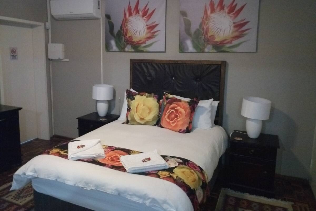 A hotel room with a bed, two nightstands, two wall-mounted lamps, and two paintings of flowers.