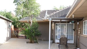 Un espacio de patio cubierto con piso de baldosas, una silla y una planta en maceta.