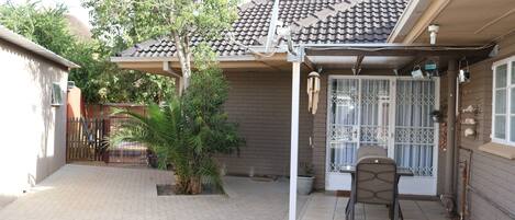 A covered patio area with a tiled floor, a chair, and a potted plant.