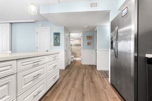 Una cocina moderna con armarios blancos, un refrigerador de acero inoxidable y piso de madera.
