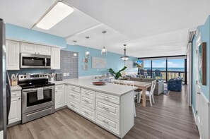 A modern kitchen with white cabinetry, stainless steel appliances, and a central island.