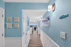 Un pasillo con piso de madera, paredes azul claro y decoración mural.