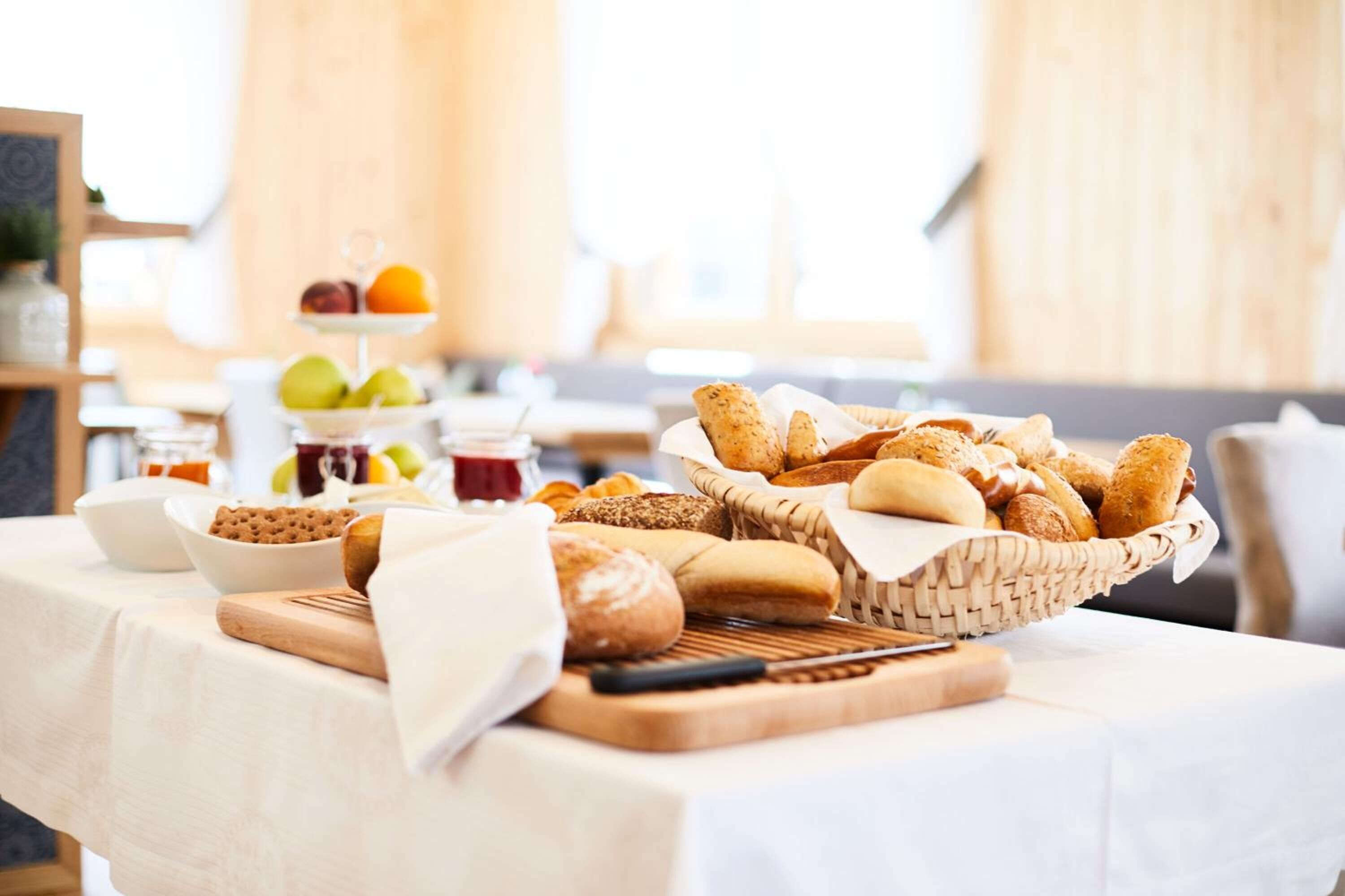 Un bufé de desayuno con panes, bollería y frutas variadas.