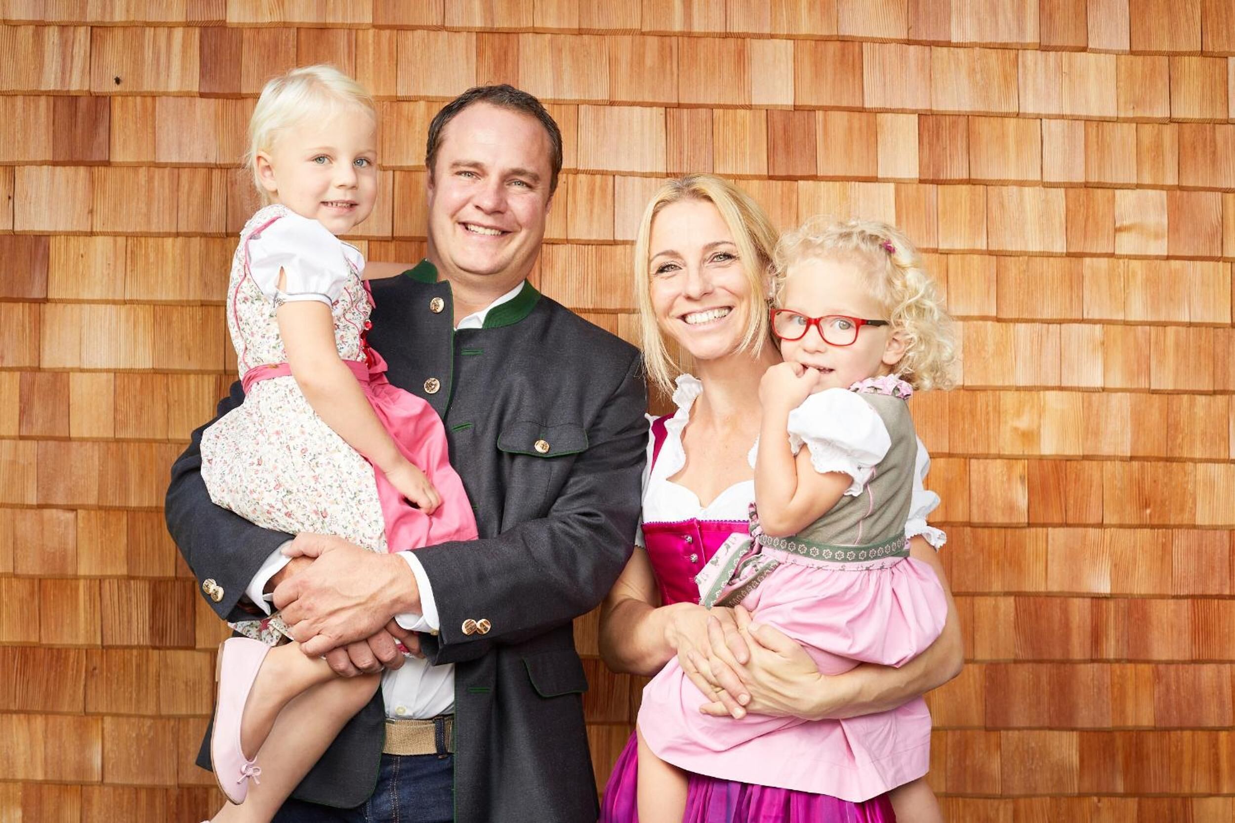 Una familia de cuatro personas vestidas con ropa tradicional frente a un panel de madera.