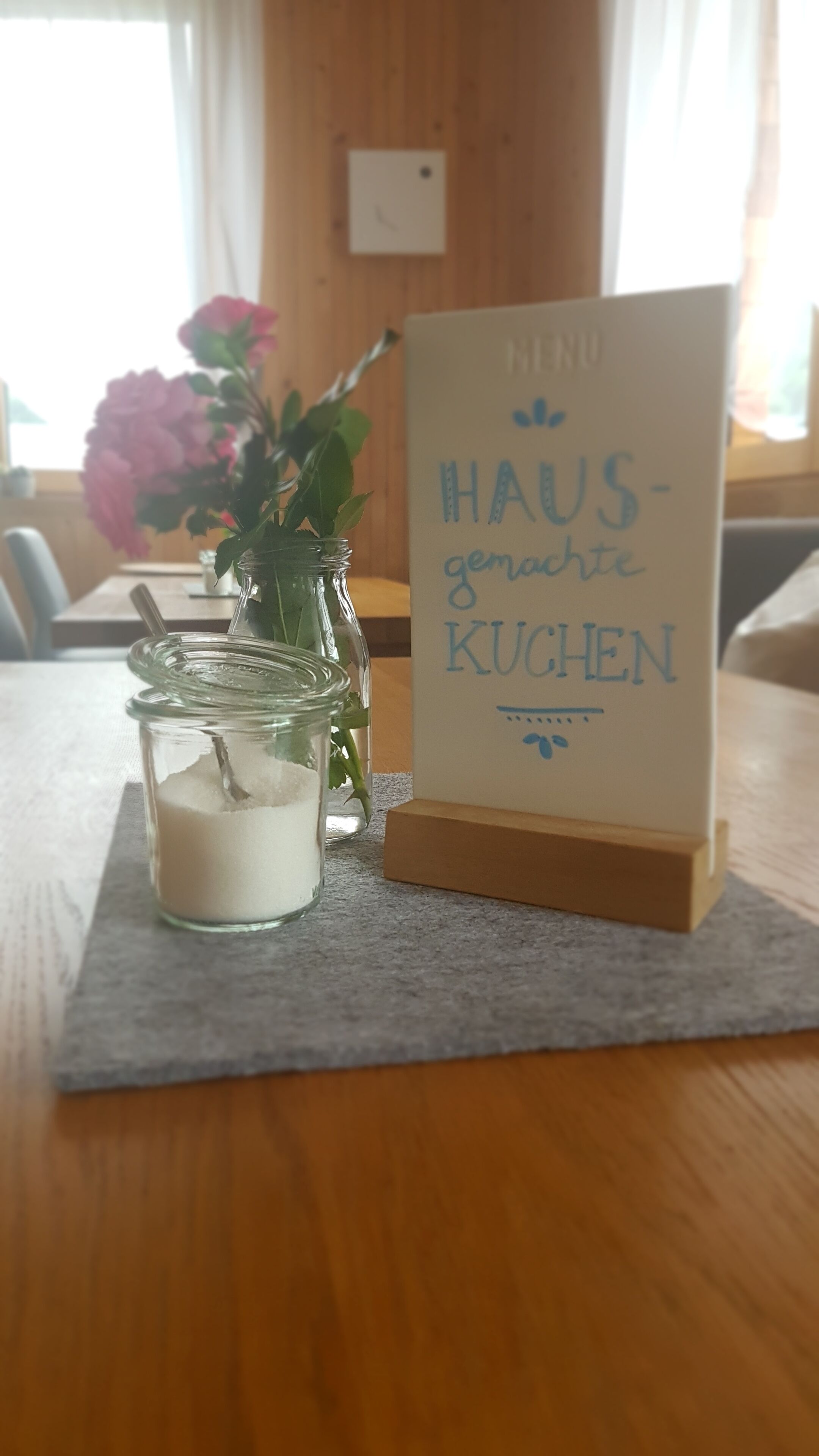 A table with a sign reading "HAUS gemachte KUCHEN" and a candle in a jar.
