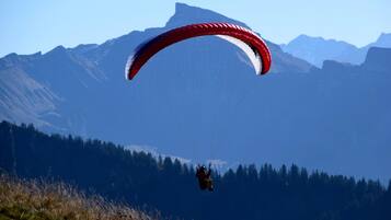 Un parapentista con un paracaídas rojo y blanco vuela sobre un paisaje montañoso.