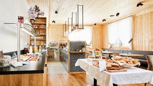 A modern kitchen with wooden accents, a buffet setup, and a seating area with a table set for dining.