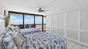 A bedroom with a large bed, a ceiling fan, and a view of the ocean through large windows. - Gulf Shores 506 Fifth Floor Beachfront View 2 Bedroom 2 Bathroom Condo (Port Aransas)