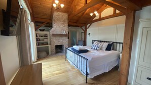 A bedroom with a bed, a wooden ceiling, a brick fireplace, and a wooden floor. - 1818 Modern Farm House with Pool, Hot Tub and a large permanent dock on the lake (Canandaigua)