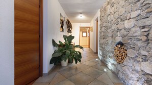 A hallway with a wooden door, potted plants, a stone wall, and a fireplace. - Landhaus Waldhart - Cozy apartment with garden & Summer Card (Umhausen)
