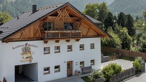 A traditional wooden chalet with a balcony, set against a mountainous backdrop. - Landhaus Waldhart - Cozy apartment with garden & Summer Card (Umhausen)
