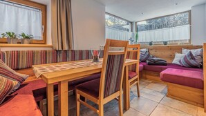 A cozy room with a wooden table, striped cushions, and a bench. - Landhaus Waldhart - Cozy apartment with garden & Summer Card (Umhausen)