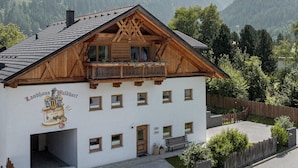 A traditional wooden chalet with a balcony, set against a mountainous backdrop.