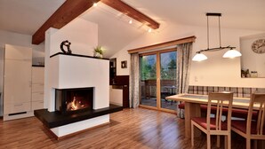 A modern kitchen with a fireplace, wooden flooring, and a dining area with a table and chairs.