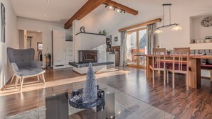 A spacious living area with a fireplace, wooden dining table, and a glass coffee table.