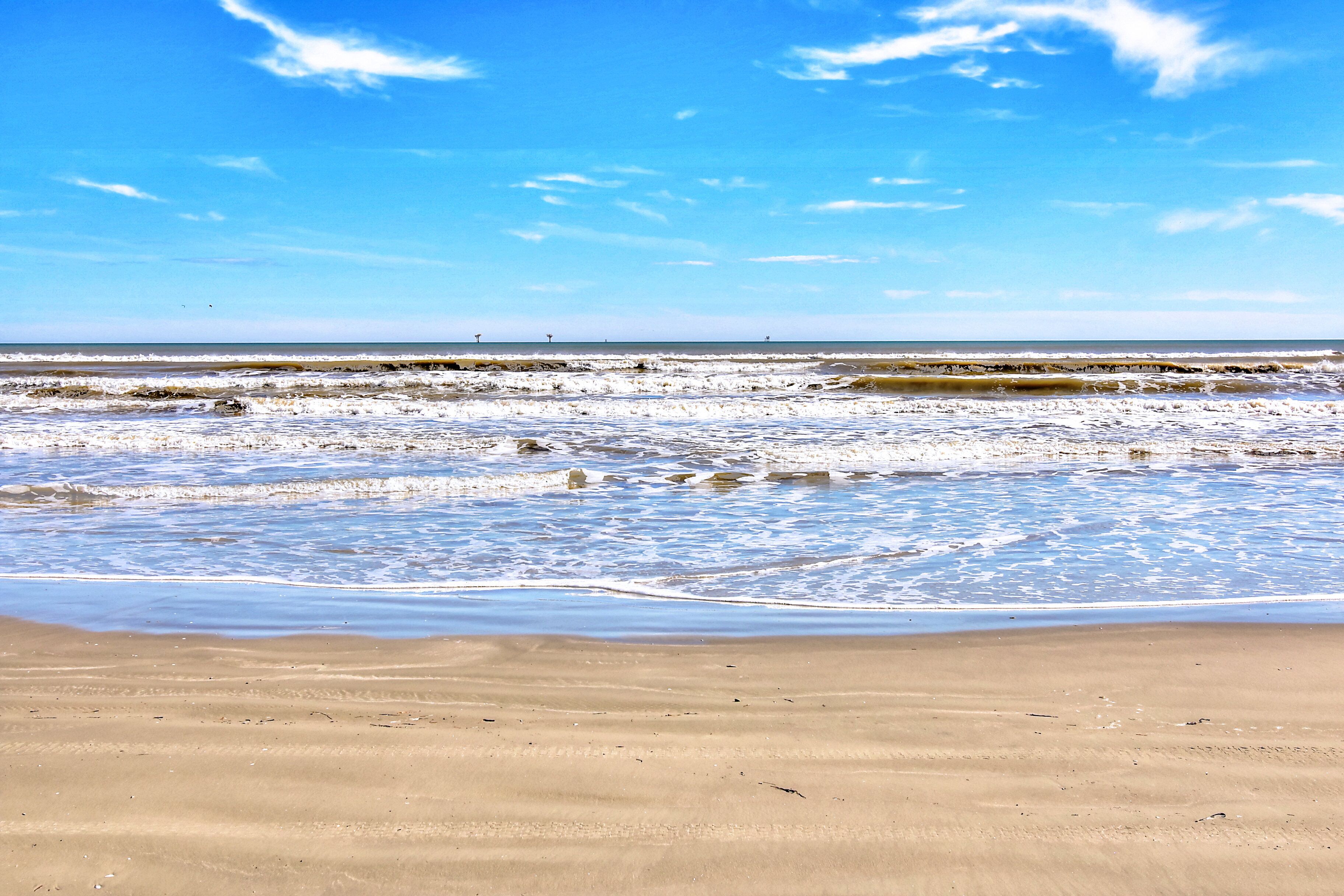 Una playa con cielo despejado y mar tranquilo.