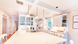 A spacious kitchen with a large island, white cabinetry, pendant lighting, and a view of the outdoors. - Lovely Lake Escape on Lake Oconee with game room, hot tub and fire pit (Eatonton)