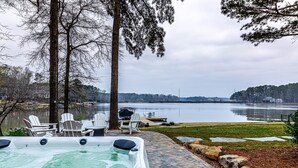 A hot tub with chairs, a dock, and a view of a lake. - Lovely Lake Escape on Lake Oconee with game room, hot tub and fire pit (Eatonton)