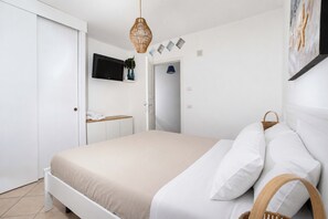 Ein Schlafzimmer mit einem Bett, einem Fernseher an der Wand und einer Tür zu einem anderen Raum.