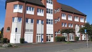 Un edificio residencial de varios pisos con fachada de ladrillo, ventanas grandes y techo plano.