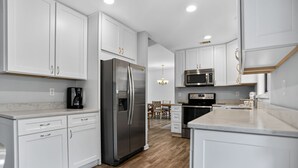 Una cocina moderna con armarios blancos, electrodomésticos de acero inoxidable y un comedor de madera.