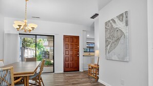 Un comedor amplio con una mesa y sillas de madera, una araña y una obra de arte grande en la pared.