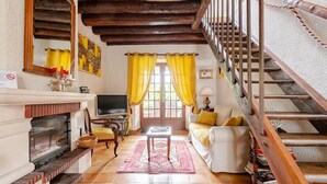 A cozy living room with a fireplace, a television, and a staircase.