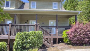 A two-story house with a front porch, a staircase, and a small garden area with bushes. - Alpine Bear Trail - Comfortable Townhome in the Innsbruck Golf Community (Helen)