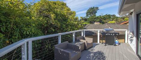 Une terrasse dotée de meubles en osier et d’un barbecue.