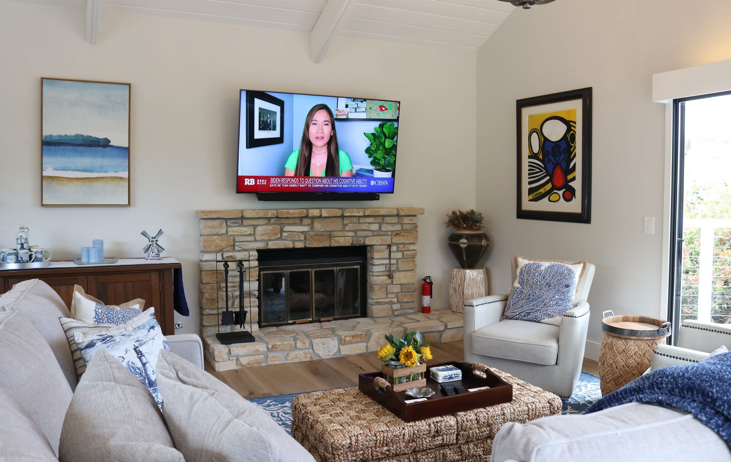 A living room with a stone fireplace, a television mounted above it, and a sofa.