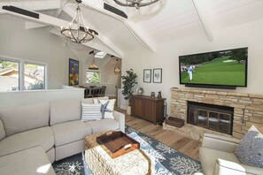 A living room with a large television, a fireplace, a sofa, and a dining area.