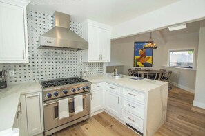 A kitchen with white cabinets, a stainless steel stove, and a tiled backsplash.