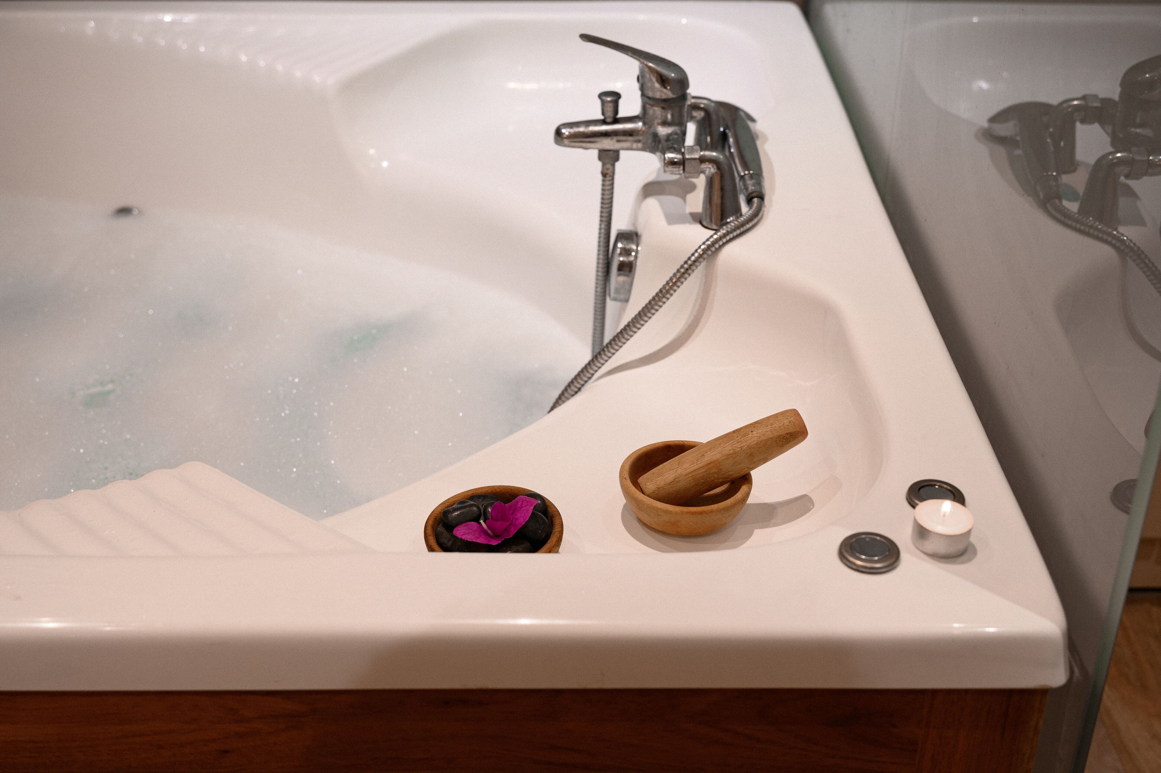 Une baignoire, un maillet en bois, une pierre ornée d’une fleur et un petit récipient.