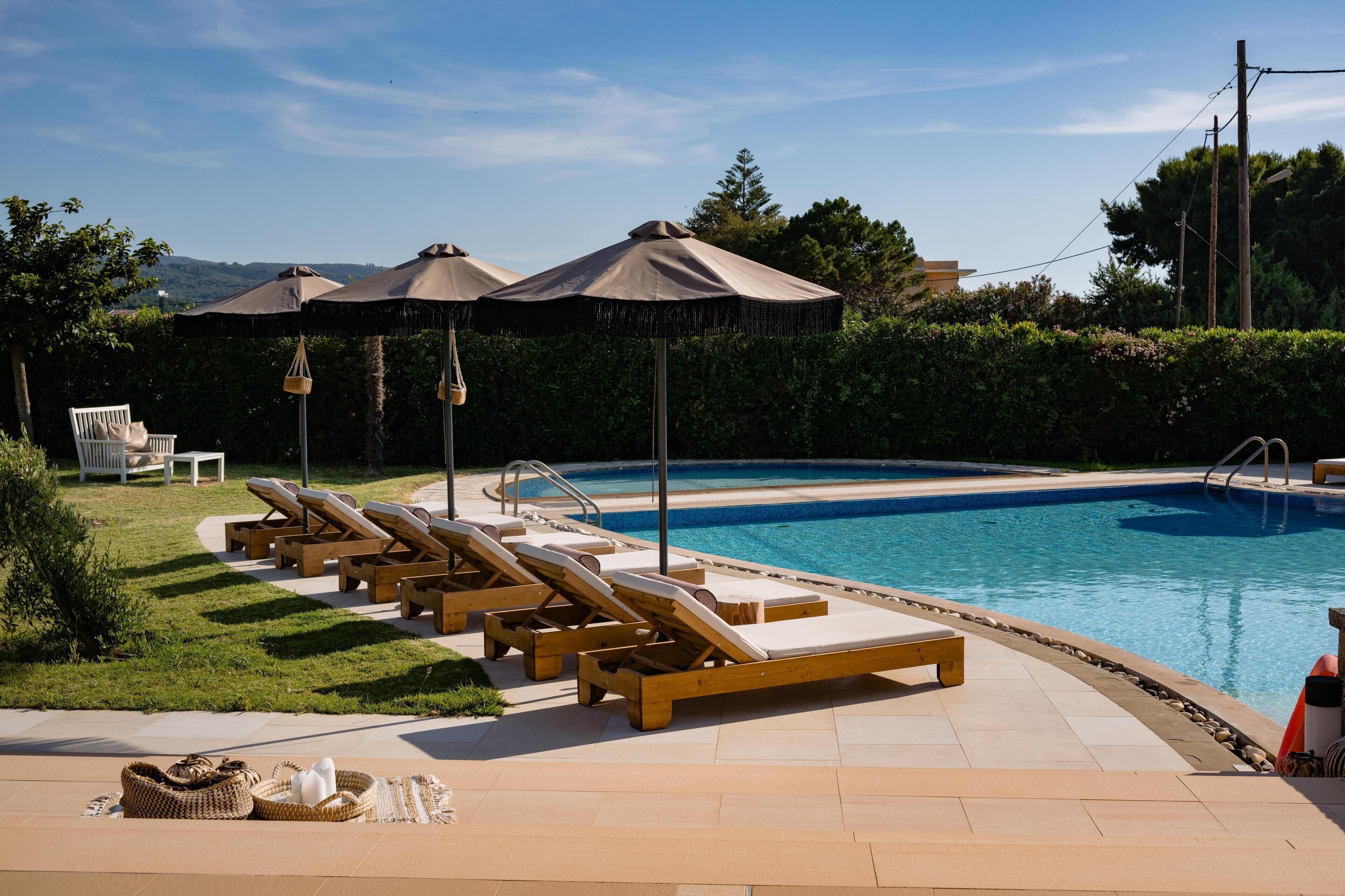 A poolside area with lounge chairs, umbrellas, and a pool.