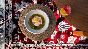 Una estera tejida con un plato de comida y un vaso de bebida sobre una alfombra estampada.