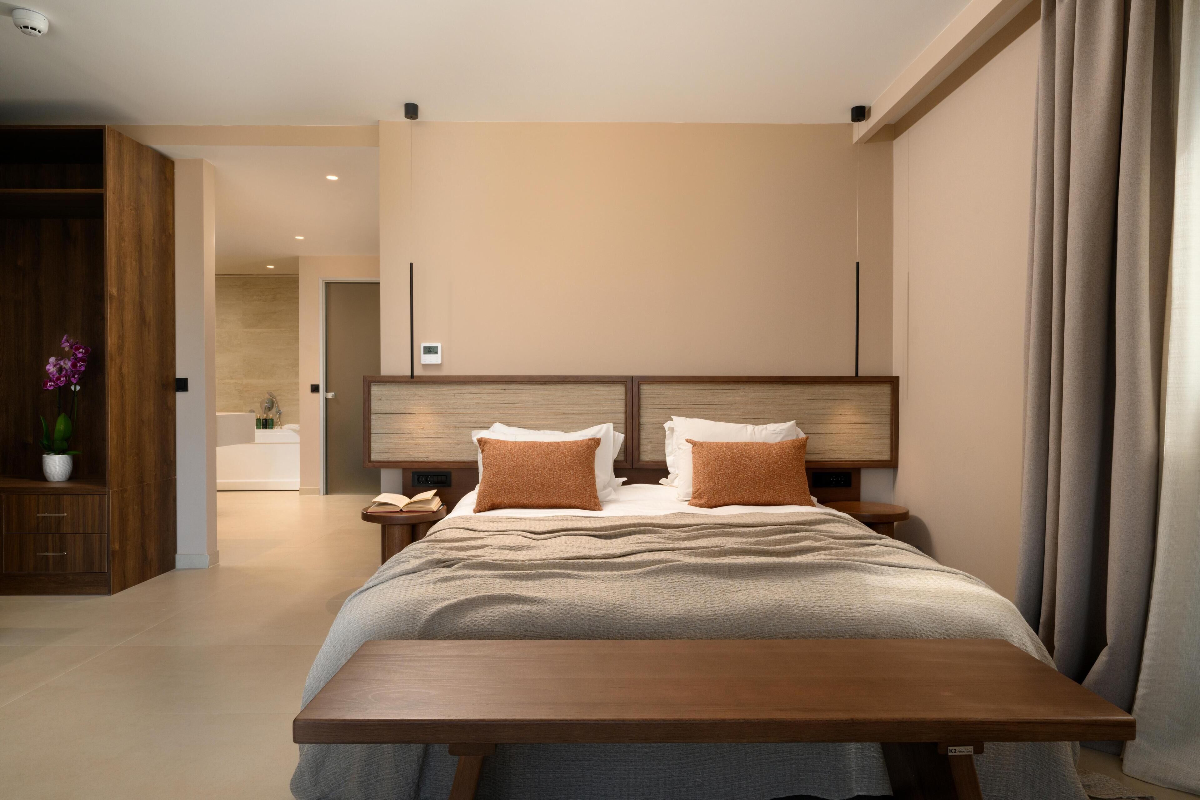 Una habitación de hotel moderna con una cama de madera, una mesita de noche y vistas al baño.
