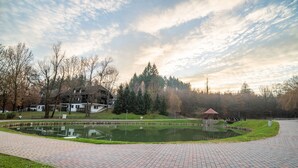 A paved pathway leading to a pond with a gazebo in the background. - Apartments Amy (Podcetrtek)