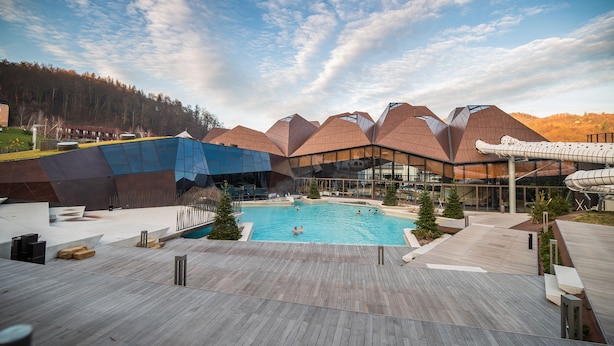 A modern building with a pool and wooden deck. - Apartments Amy (Podcetrtek)