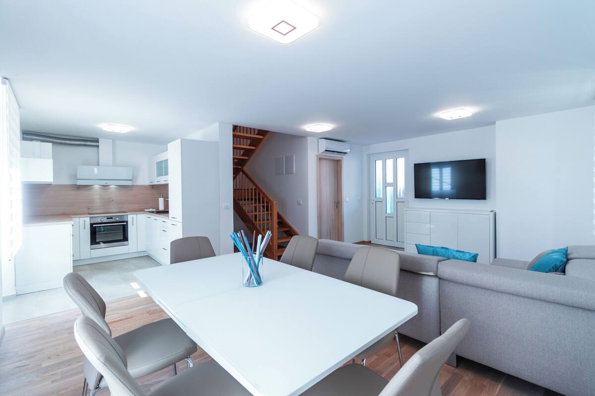 A modern living space with a kitchen, dining area, and a staircase leading to another level.