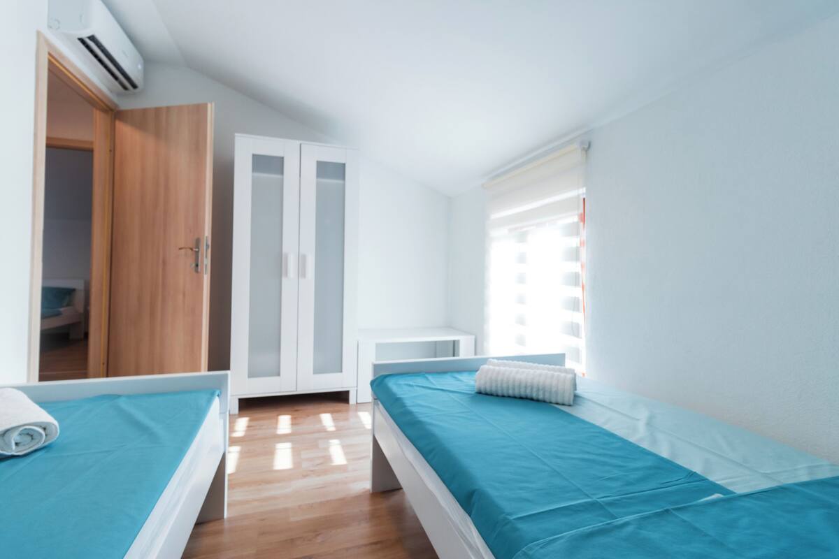A bedroom with two beds, a wardrobe, and a window with blinds.
