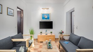 Una sala de estar moderna con dos sofás, una mesa de centro, un televisor y un mueble de madera con plantas.