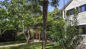 Un edificio de piedra con jardín, destacando palmeras y diferentes arbustos.
