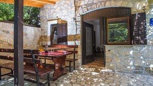 Un patio al aire libre con paredes de piedra, mobiliario de madera y piso de piedra.