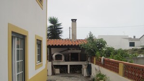 A narrow alleyway with a small courtyard, a tiled roof structure, and a garden area with plants and flowers. - Between Nazareth and S. Pedro de Moel (Pataias)