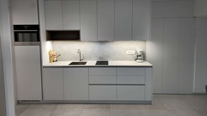 Uma cozinha moderna com armários cinza, forno embutido, pia dupla e máquina de café.