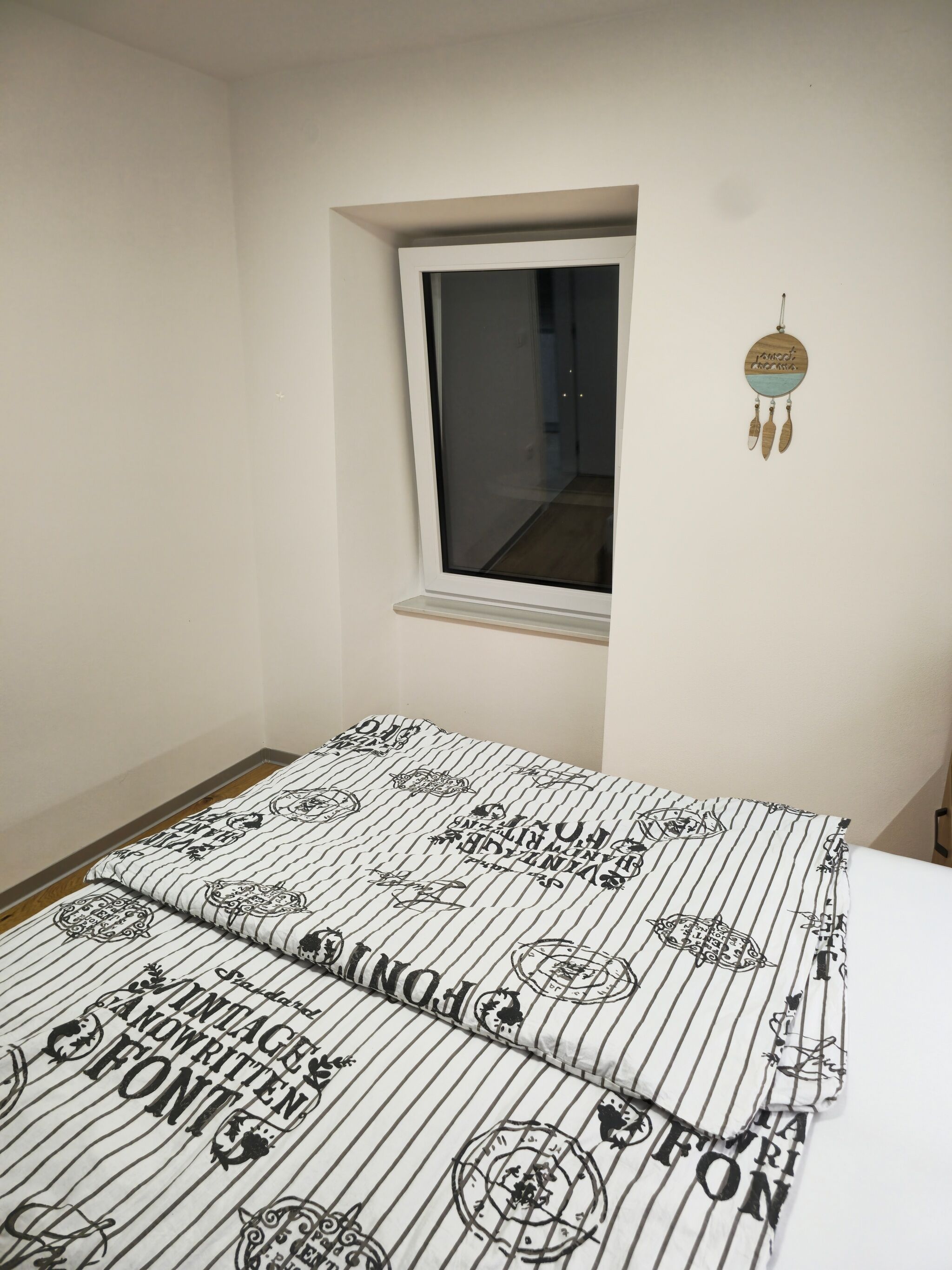 A bedroom with a bed, a window, and a wall decoration.