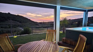 Conjunto de mesa e cadeiras de madeira montado num pátio, com vista para uma banheira de hidromassagem e uma paisagem deslumbrante.