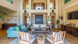 A spacious living area with a high ceiling, a central coffee table, two sofas, and a fireplace.