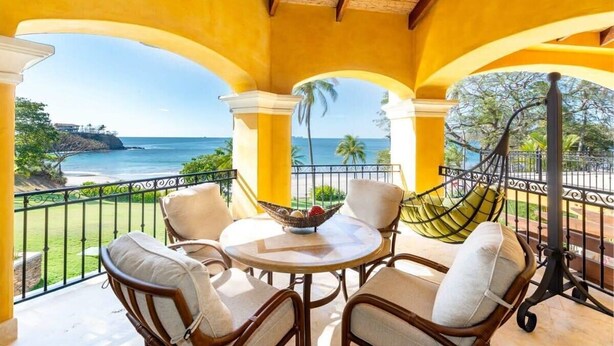 A covered outdoor seating area with a view of the ocean and a hammock.